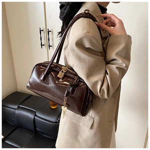 Detail of dark brown glossy Boston bag with metal lock charm and vintage texture