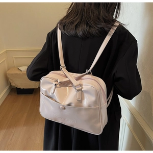 Detail of light pink patent leather backpack with adjustable straps on a model's back