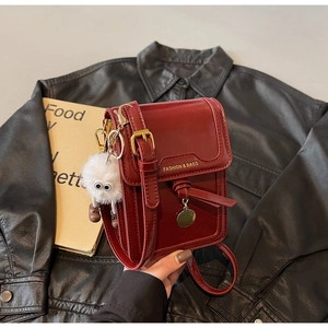 Detail of burgundy leather mini crossbody bag with gold buckle and white fur charm