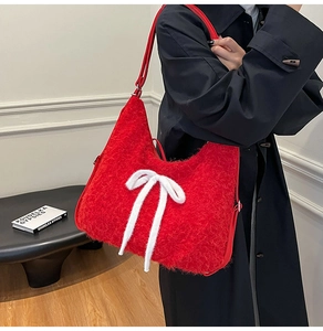 Close-up of red plush shoulder bag with a large white bow and soft fuzzy texture