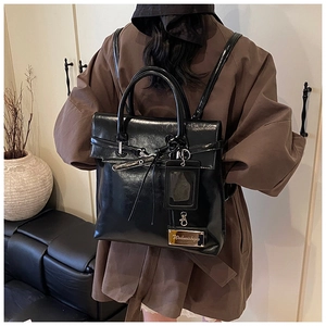 Détail d'un sac à dos vintage en cuir noir brillant avec plaque dorée et porte-cartes