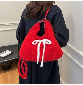 Detail of red plush tote bag with white knitted bow and red leather shoulder strap