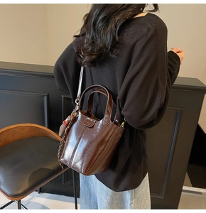 Detailed view of dark brown bucket bag featuring a glossy finish and cute bear charm