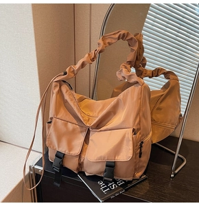 Detail showing the large pockets and unique ruffled shoulder strap of this khaki tote bag