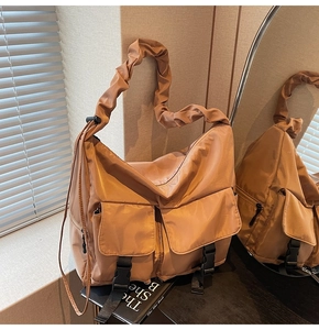 Detail of caramel nylon tote bag with large front pockets and stylish pleated shoulder strap