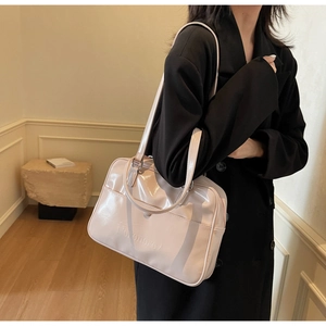 Close-up of pink patent leather shoulder bag with embossed logo and adjustable strap