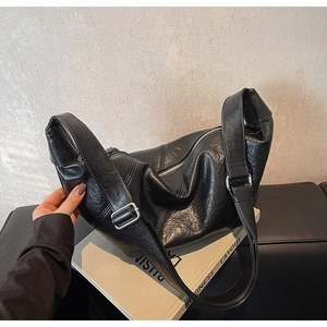 Detail view of black pleated PU leather hobo bag with silver buckle and adjustable strap