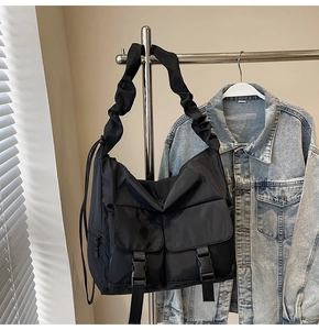 Detail of black waterproof nylon tote bag with utility buckle pockets and pleated shoulder strap