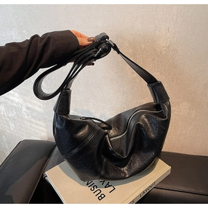 Detail of black wrinkled texture and silver zipper on the large crescent shoulder bag