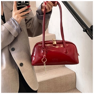 Detail of dark red patent leather bowling bag with gold hardware and logo engraving