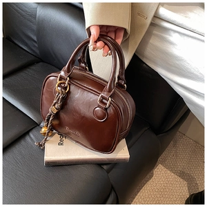 Close-up of vintage brown leather handbag featuring timelo logo and braided charm