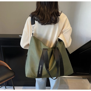 Sac cabas en nylon vert olive avec larges bandoulières griffées porté par un mannequin