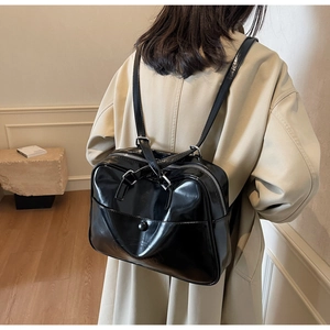 Detail of glossy black leather backpack with triangle embossed pattern and silver zipper