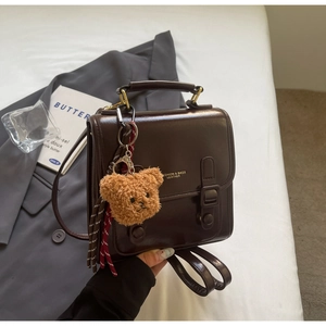 Nahaufnahme des Retro-Lederrucksacks in Schokoladenbraun mit süßem Teddybär-Anhänger