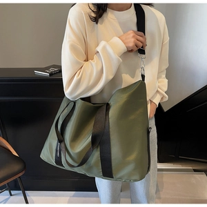 Détail macro du sac cabas en nylon vert olive avec larges sangles et étiquette logo