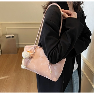 Detail of pink tote bag with cloud texture, gold logo, and white bird plush charm accessory