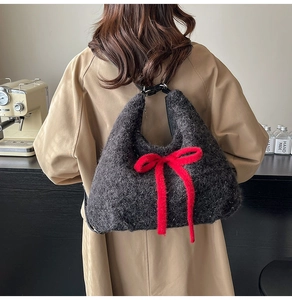 Side view of a fluffy plush tote bag with a large red bow on a model in a trench coat