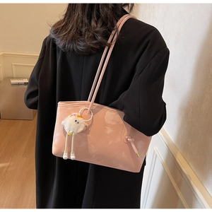 Detailed view of pink leather tote bag with dual straps and plush doll pendant
