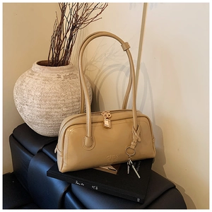 Detailed close-up of beige boston bag with gold lock and ciho embossed logo
