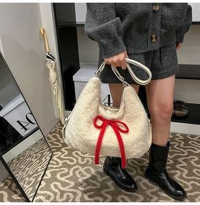 Detail of soft cream plush tote bag with a contrasting large red woven bow accent