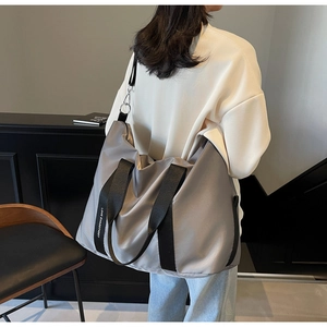 Gros plan d'un grand sac fourre-tout gris en nylon avec des bretelles lettrées sur un modèle