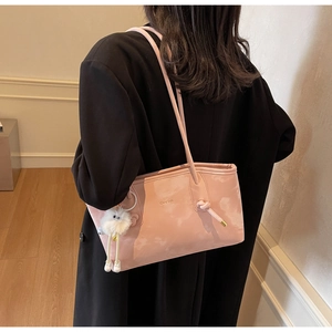 Detail of pink marble textured tote bag with knot strap and plush charm on black coat