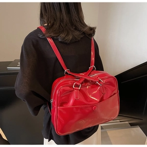 Detail of red glossy leather backpack featuring silver hardware and adjustable straps