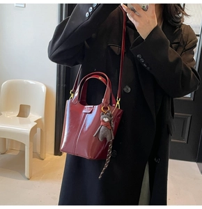 Burgundy faux leather bucket bag shown as a crossbody with scarf and bear pendant detail
