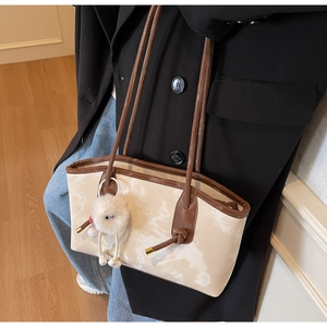 Detail of cream marble pattern tote bag with brown leather straps and plush charm