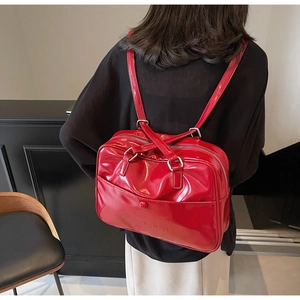 Detail of red patent leather backpack with glossy finish and silver metal hardware accents