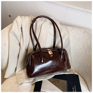 Detail of dark brown glossy bowling bag with gold padlock and adjustable shoulder strap