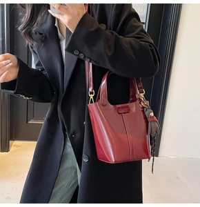 Burgundy bucket bag with decorative stitching and cute teddy bear charm accessory
