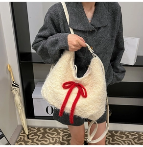 Detail of plush cream shoulder bag featuring a large red velvet bow and leather strap