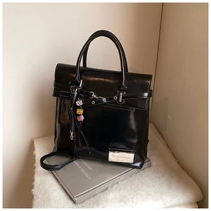 Détail du sac à dos en cuir noir brillant avec sangle à boucle et breloques dés