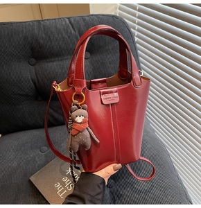 Detail of wine red bucket bag with bear charm and adjustable shoulder strap