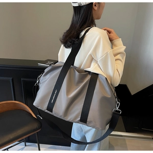 Détail du cabas en nylon gris avec sangle à logo et bandoulière réglable pour le voyage