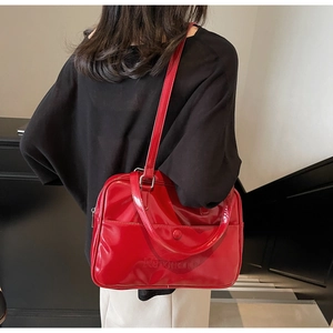 Detail of red patent leather shoulder bag with glossy finish and logo engraving