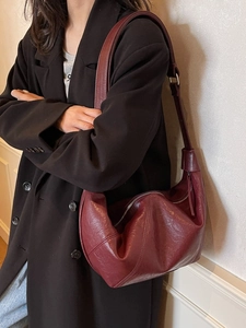Burgundy pleated faux leather hobo shoulder bag with adjustable strap on model