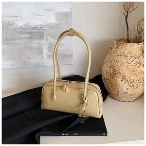 Detailed view of beige Boston bag with long top handles and metallic lock charm