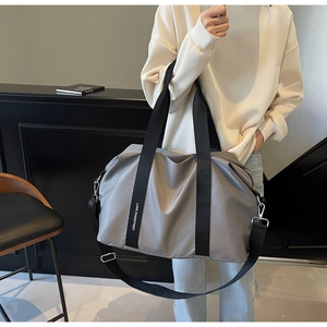 Détail du sac fourre-tout gris en nylon avec sangle logo et bandoulière réglable