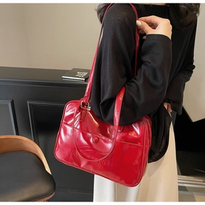 Macro shot of glossy red tote bag with embossed letters and double shoulder straps