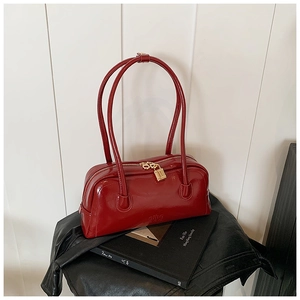 Detailed shot of dark red patent leather handbag featuring a vintage golden lock zipper