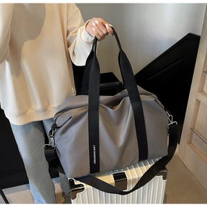 Gros plan du sac de voyage en nylon gris avec sangles griffées près d'une valise blanche