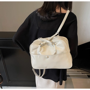 Detail of creamy white patent leather backpack with adjustable straps and silver hardware