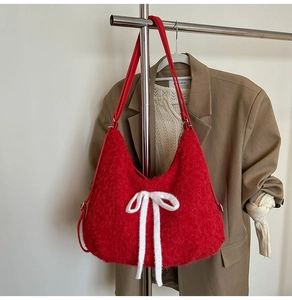 Detail of red plush shoulder bag with white knit bow and adjustable faux leather straps