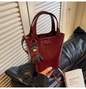 Close-up of wine red bucket bag in glossy leather with cute bear charm and fine details