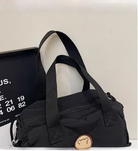 Dettaglio della borsa tote in tela nera con manici rinforzati e toppa con orsetto marrone