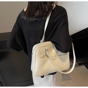 Detail of cream glossy shoulder bag with embossed logo and functional front pocket