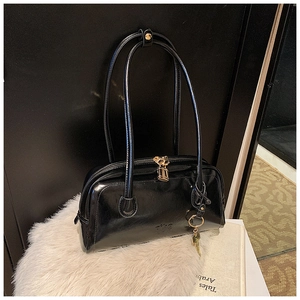 Detail of vintage black glossy leather handbag with gold hardware and key pendant