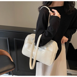 Detail of embossed logo on cream patent leather shoulder bag with smooth glossy finish